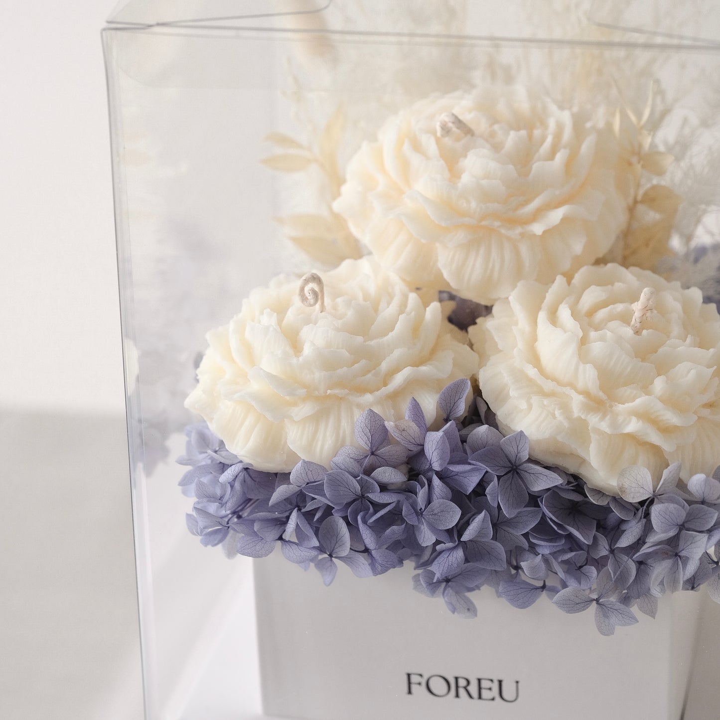 Close up image of premium flower box in midnight blue colourway with three lightly scented soy wax candles included that are in a peony flower shape.