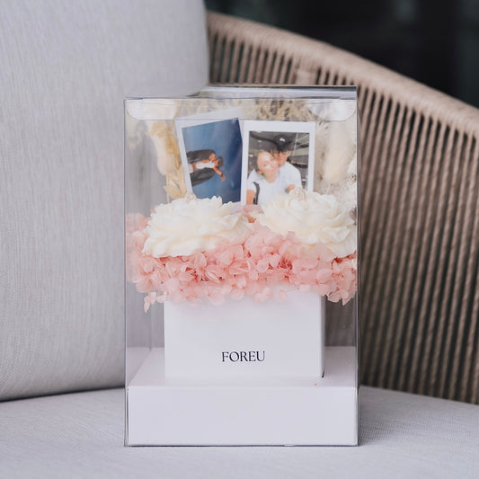 Decorative photo frame with flowers and photos on a surface in a premium flower box arrangement with polaroids